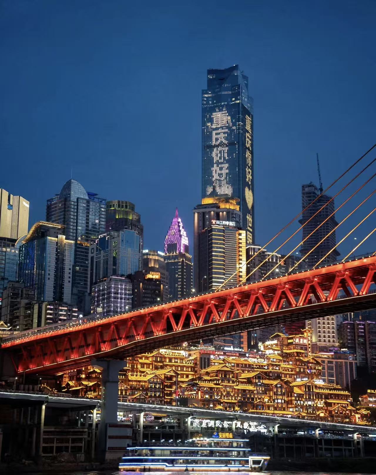 Hongyadong and the Qiansimen Bridge illuminated beside the river at night